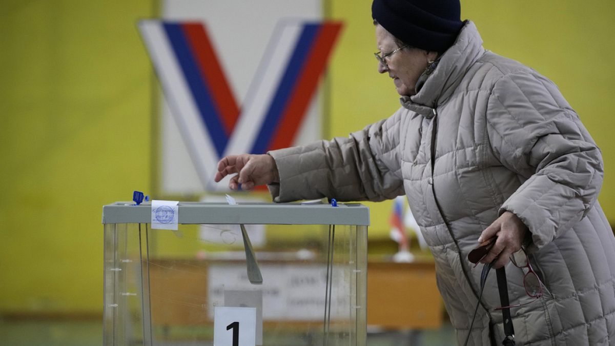 A woman casts a ballot at a polling station located in the school gymnasium during a presidential election in St. Petersburg, Russia, Friday, March 15, 2024. 