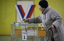 A woman casts a ballot at a polling station located in the school gymnasium during a presidential election in St. Petersburg, Russia, Friday, March 15, 2024. 