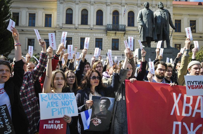 People hold sheets reading "enough" as they protest in downtown Tbilisi, Georgia, Sunday, March 17, 2024.