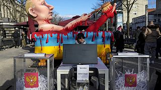 Макет урны для голосования с порванными бюллетенями и моделью президента Путина во время акции протеста возле избирательного участка у посольства России в Берлине