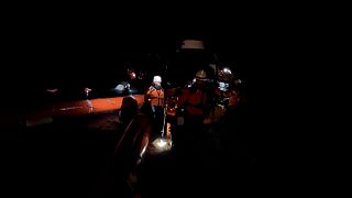 Imagen de una operación de rescate de una embarcación con inmigrantes a la deriva, durante la noche, en aguas del mar Mediterráneo.