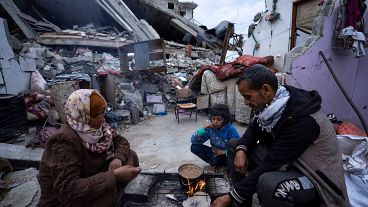 عائلة فلسطينية تقتسم وجبة طعام وسط ركام بيتهما الذي دمره القصف الإسرائيلي 