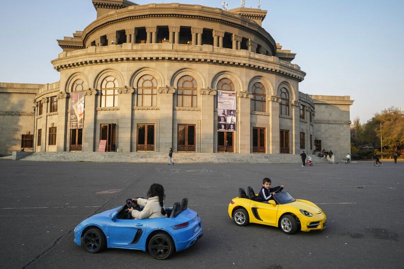 Children ride toy cars in Freedom Square in Yerevan, November 2021