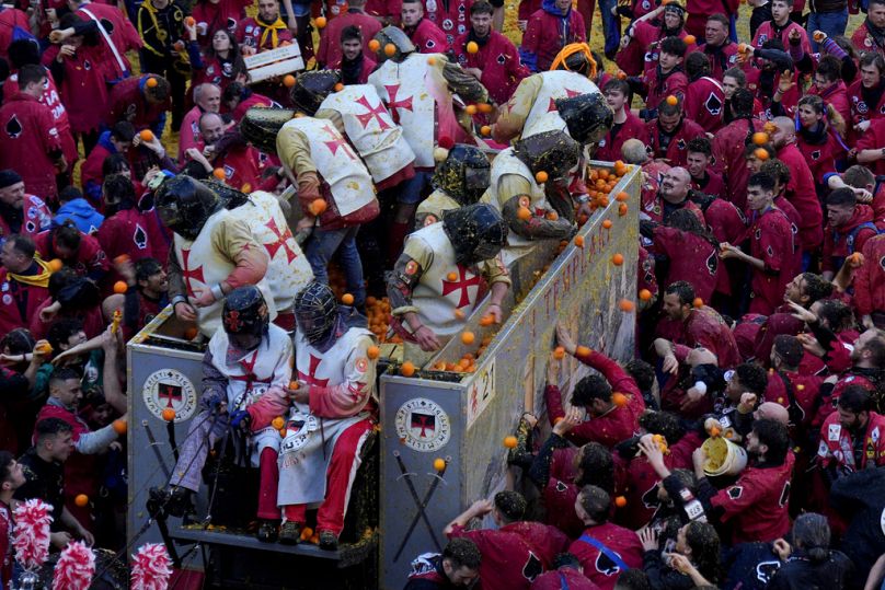 People wearing protection helmets and costumes pelt each other with oranges during the 'Battle of the Oranges" part of Carnival celebrations in Ivrea, Italy.