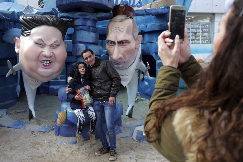 People take pictures by statues of North Korean leader Kim Jong Un, left, and Russian President Vladimir Putin as sharks during Carnival celebrations in Torres Vedras.