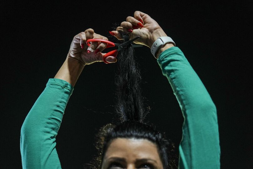 A woman cuts her hair in solidarity with Iranian women during a protest in Tel Aviv, Saturday, Oct. 29, 2022.