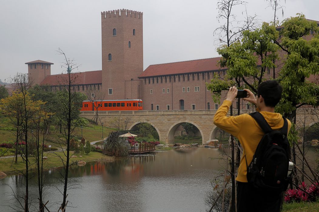 A man takes a photo of a train in the Huawei's Ox Horn campus in Songshan Lake