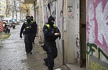 Police officers walk up to the entrance of a building during a raid in Berlin, Germany, Thursday, Nov. 23, 2023.