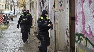 Police officers walk up to the entrance of a building during a raid in Berlin, Germany, Thursday, Nov. 23, 2023.