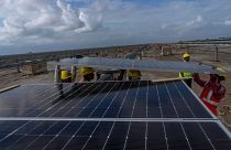 کارگران در حال نصب پنل‌های خورشیدی در پارک انرژی‌های تجدیدپذیر شرکت آدانی در صحرای نمک در نزدیکی خاودا هستند