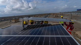 کارگران در حال نصب پنل‌های خورشیدی در پارک انرژی‌های تجدیدپذیر شرکت آدانی در صحرای نمک در نزدیکی خاودا هستند