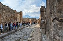 Turisták Pompeiiben, a háttérben a Vezúvval