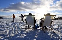 يجلس بعض الأشخاص تحت أشعة الشمس ويستمتعون بالطقس الشتوي المشمس، بينما يتزلج البعض الآخر على الجليد في هلسنكي، فنلندا، في يوم عيد الحب في 14 فبراير 2021.