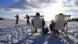 يجلس بعض الأشخاص تحت أشعة الشمس ويستمتعون بالطقس الشتوي المشمس، بينما يتزلج البعض الآخر على الجليد في هلسنكي، فنلندا، في يوم عيد الحب في 14 فبراير 2021.