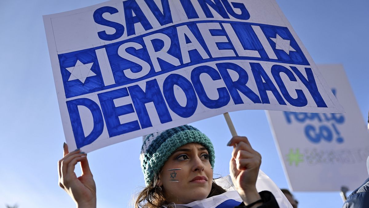 متظاهرة تحمل لافتة كتب عليها "إنقاذ الديمقراطية الإسرائيلية" برلين، ألمانيا.