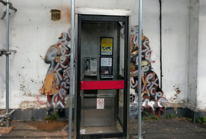 A view of the Banksy mural which targets the issue of Government surveillance with silver and red paint sprayed over it, Cheltenham, England.