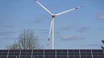 Imagen de una turbina eólica detrás de un tejado con módulos solares en Werl, Alemania.