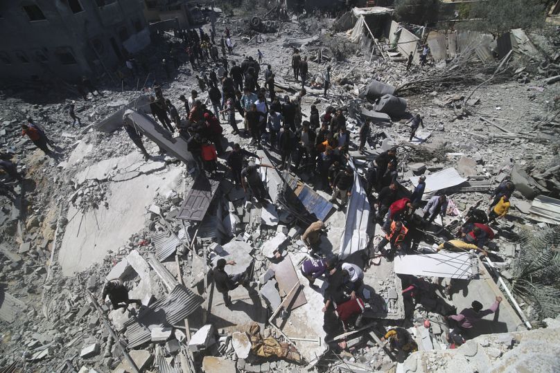 alestinians look at a residential building destroyed in an Israeli strike in Rafah, Gaza Strip