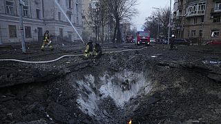 Firefighters work near the crater at the site after Russian attacks in Kyiv, Ukraine on March 21.