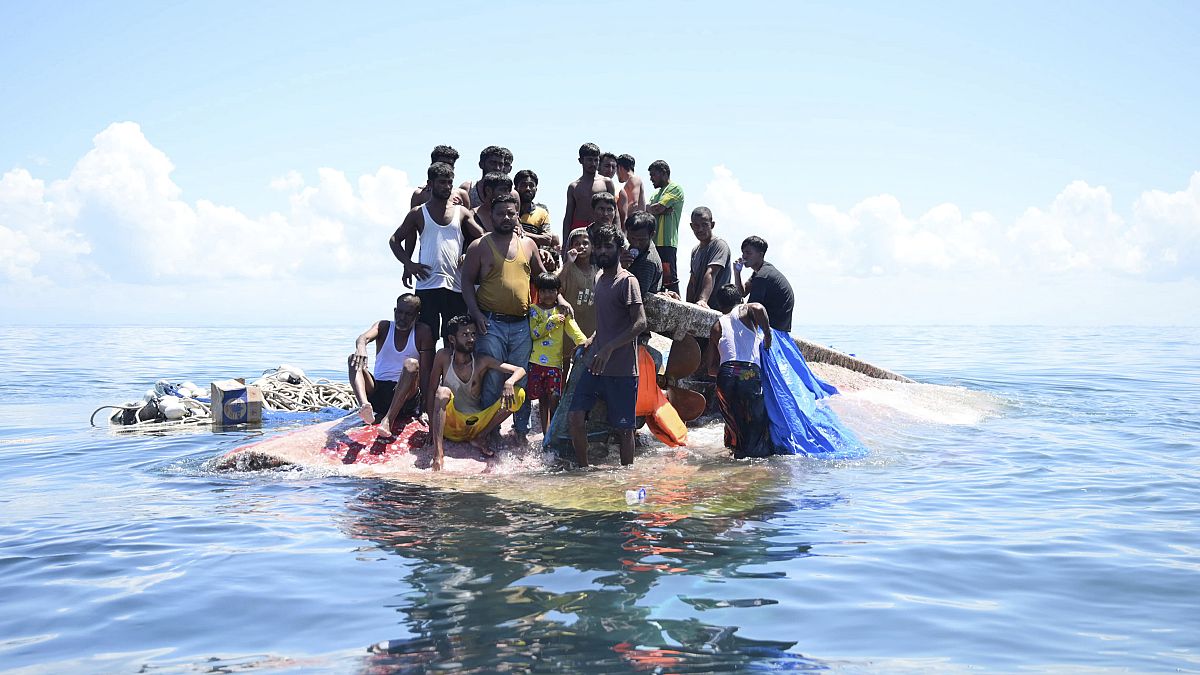 لاجئون من الروهينجا يقفون على متن قاربهم المنقلب قبل أن يتم إنقاذهم في المياه قبالة غرب آتشيه