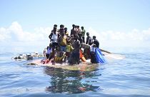 لاجئون من الروهينجا يقفون على متن قاربهم المنقلب قبل أن يتم إنقاذهم في المياه قبالة غرب آتشيه