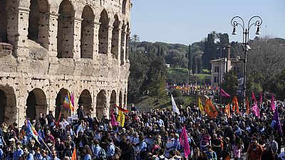 Demonstrators walk past the Colosseum in Rome, Italy, Thursday, March 21,