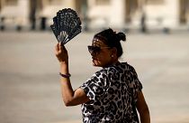 A woman uses a fan in the courtyard of the Louvre museum, September 2023, in Paris.