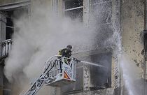 Ukraynalı itfaiye erleri, Rusya tarafından başkent Kiev'e atılan füzelerin enkazının çarptığı binalarda çıkan yangını söndürürken
