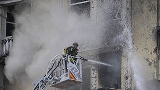 Ukraynalı itfaiye erleri, Rusya tarafından başkent Kiev'e atılan füzelerin enkazının çarptığı binalarda çıkan yangını söndürürken