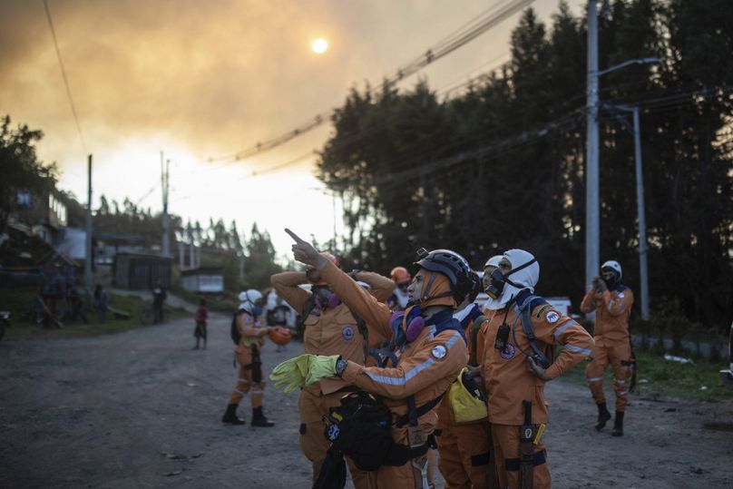 Rescue workers point at a fire burning on the slopes of the mountains surrounding Nemocon, north of Bogota, January 2024