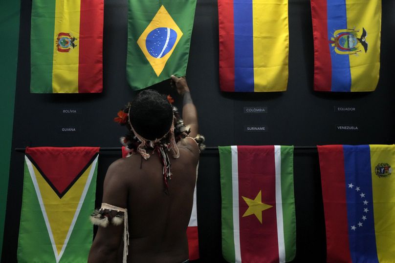 Un indígena pasa su mano sobre la bandera brasileña durante las reuniones del Diálogo Amazonas en el centro de convenciones Hangar en Belem, agosto de 2023.