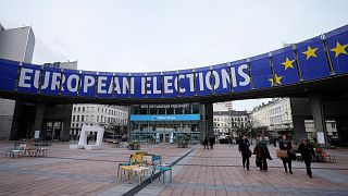 People walk under a banner advertising the European elections outside the European Parliament