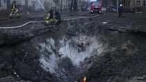 Des pompiers travaillent près du cratère sur le site après une attaque russe à Kyiv, Ukraine, jeudi 21 mars 2024.