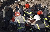 In this photo provided by the Ukrainian Emergency Service, Ukrainian emergency carry an injured person at the site of Russia's air attack in Khmelnytskyi, Ukraine, March 2024.