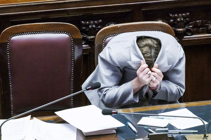 Italian Premier Giorgia Meloni hides herself in her jacket after opposition lawmaker Angelo Bonelli told her not to look at him with a "disturbing look", in Rome, March 2024