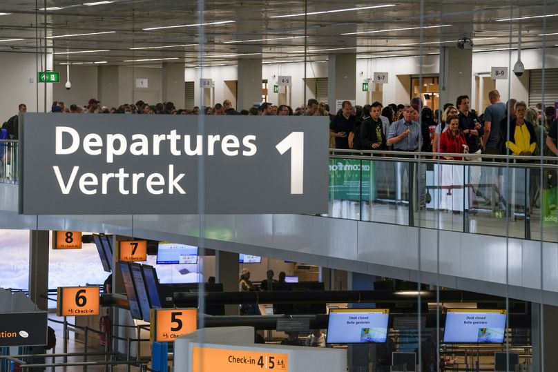 Travelers wait in long lines to check in and board flights at Amsterdam's Schiphol Airport.
