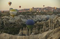 Des montgolfières, transportant des touristes, s'élèvent dans le ciel, au-dessus des « cheminées de fées » en Cappadoce, au centre de la Turquie.