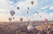 Des montgolfières, transportant des touristes, s'élèvent dans le ciel, au-dessus des « cheminées de fées » en Cappadoce, au centre de la Turquie.