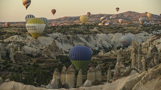 Unos globos aerostáticos con turistas se elevan sobre las Chimeneas de Hadas de Capadocia, ubicadas en el centro de Turquía.