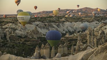 Hot air balloons, carrying tourists, rise into the sky above the "fairy chimneys" in Cappadocia, central Türkiye.