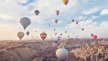 Unos globos aerostáticos con turistas se elevan sobre las Chimeneas de Hadas de Capadocia, ubicadas en el centro de Turquía.