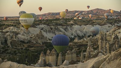 Hot air balloons, carrying tourists, rise into the sky above the "fairy chimneys" in Cappadocia, central Türkiye.