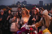 People lay flowers and light candles standing next to the Crocus City Hall, on the western edge of Moscow, Russia, Saturday, March 23, 2024. 