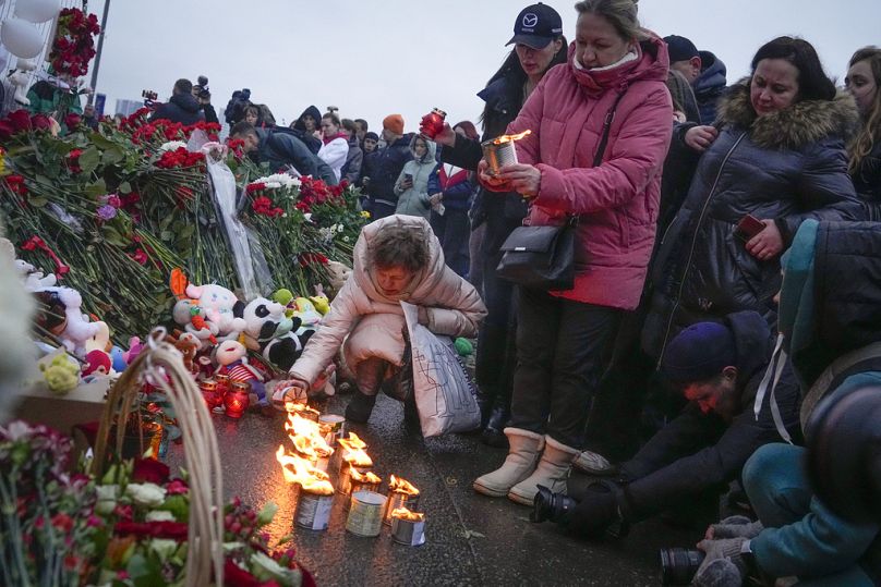 Eine Frau zündet Kerzen am Zaun neben der Crocus-City-Hall am westlichen Rand von Moskau an, 23. März 2024.
