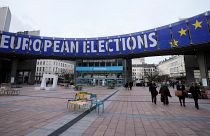 أشخاص يسيرون تحت لافتة دعائية للانتخابات الأوروبية خارج البرلمان الأوروبي في بروكسل
