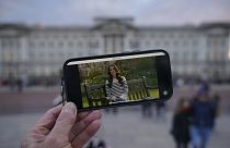 A person watches an announcement on a smart phone outside Buckingham Palace by Kate, the Princess of Wales, Friday, March 22, 2024.