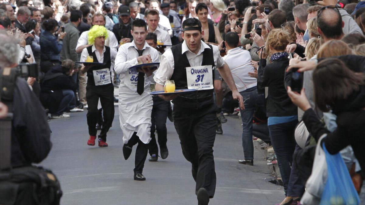FILE- People dressed as waiters carry trays of drinks as they take part in a race through the streets of Paris, 15 May, 2011. 