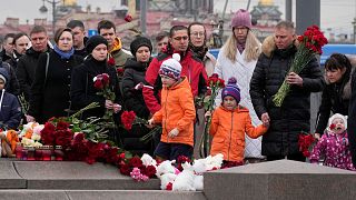 Persone depongono fiori in un monumento spontaneo in memoria delle vittime dell'attentato di Mosca a San Pietroburgo, Russia, domenica 24 marzo 2024. 