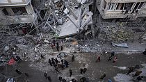 Palestinianos procuram por sobreviventes nos escombros de edifícios atingidos por um ataque aéreo israelita em Rafah