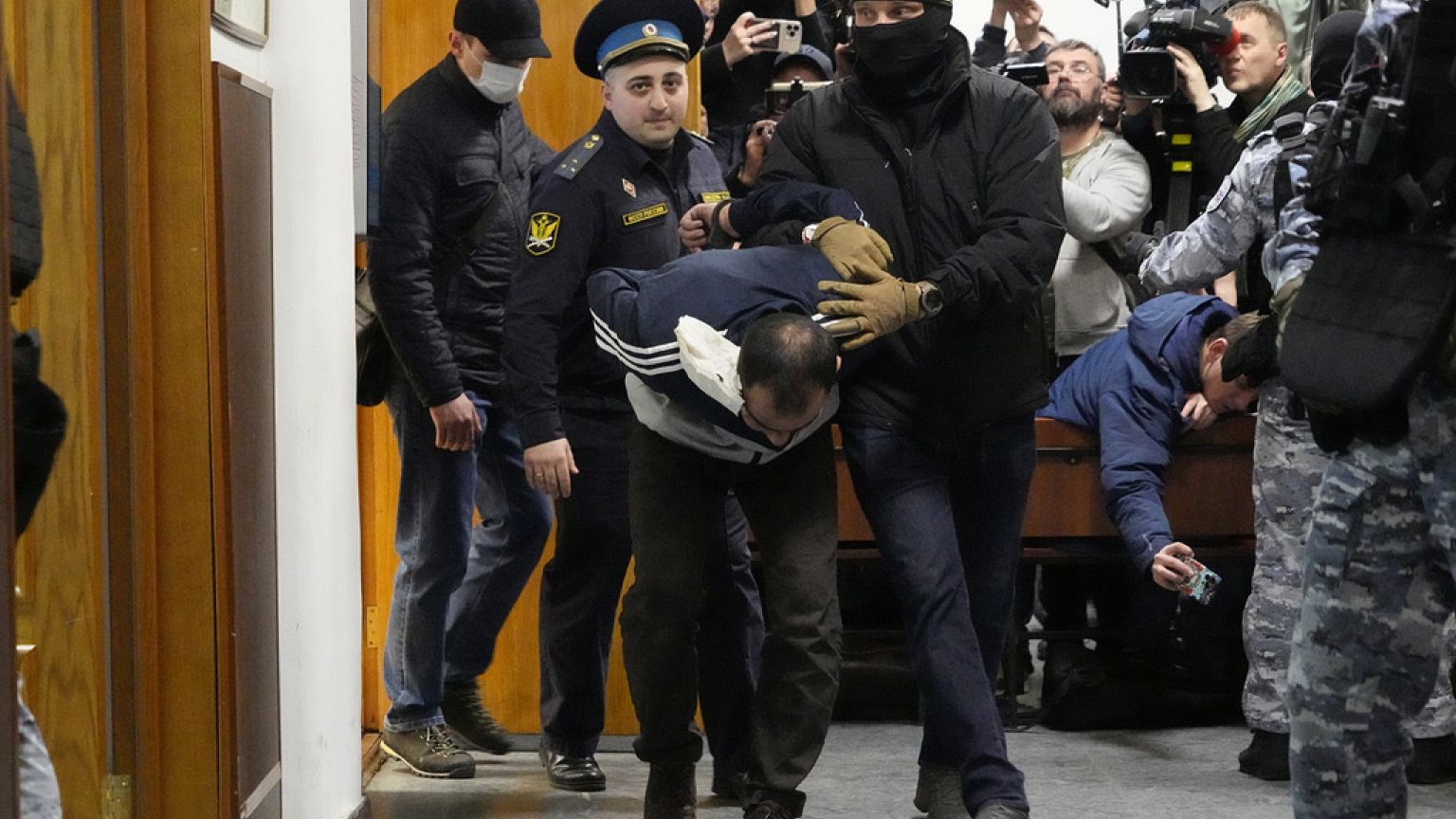 Uno de los sospechosos de llevar a cabo el atentado del viernes en el Crocus City Hall, es escoltado por policías y agentes del FSB en el Tribunal del Distrito de Basmani.